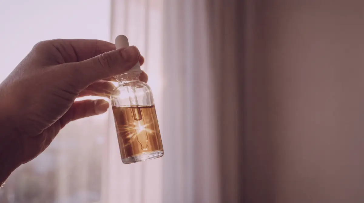 Skincare bottle held against soft morning window light