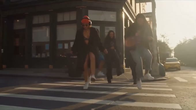 Backlit wide: she walks towards the camera into low sun with others behind her.